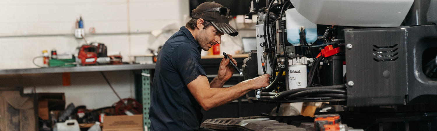A mechanic fixing a bobcat excavator